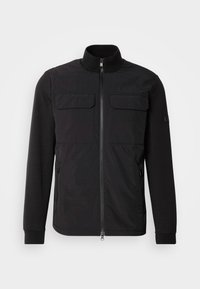 Jachetă neagră cu fermoar frontal, guler înalt, două buzunare pe piept și manșete elastice, confecționată dintr-un material ușor, texturat.