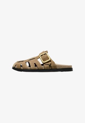 Wildleder-Sandale in Hellbraun mit Ausschneide-Design, einem breiten Riemen und einem goldenen Schnallenakzent; flache schwarze Sohle mit strukturierten Kanten.