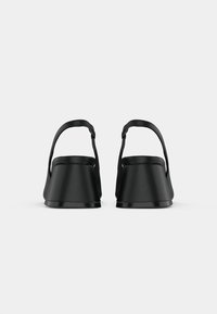 Sandales à plateforme noires avec une finition mate lisse. Elles disposent d'un bout rond et d'une fine sangle à la cheville pour un maintien sécurisé.