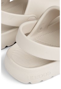 Hvite gummisandaler med en teksturert fotbunn, brede stropp, og avrundet form. Har en logo preget på sålen.