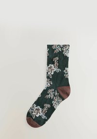 Calcetín verde oscuro con bordado floral en blanco y marrón, con acentos de talón y punta en marrón, textura suave y diseño de longitud media.