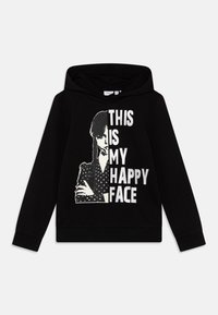 Svart hoodie med en stor grafik som har texten "DETTA ÄR MITT GLADA ANSIKTE" och en bild av en figur i en prickig topp. Mjukt tyg, sweatshirt-design.