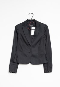 Zwarte blazer met getailleerde pasvorm, twee knopen, notch-revers en stippenvoering op de mouwen. Gladde, geweven stof. Hangt aan een zwarte haak.