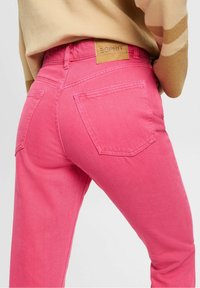 Jeans de mezclilla rosa con un corte relajado, que cuentan con dos bolsillos traseros y una etiqueta de cuero marrón con "ESPRIT" grabada en la cinturilla.