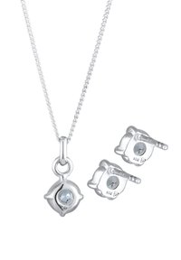 Collana d'argento con pendente circolare che presenta una gemma centrale. Accompagnata da orecchini a bottone in argento coordinati, con gemme simili.