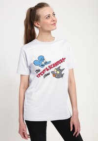Hvid bomulds t-shirt med farverige tegneserieillustrationer af en blå mus og en sort kat med teksten "The ITCHY & SCRATCHY Show."