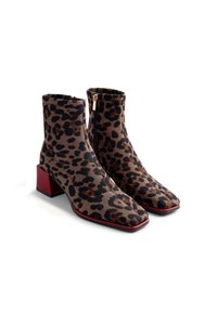 Botas de tobillo con estampado de felino, con textura acanalada, punta cuadrada y tacón cuadrado rojo. Cierre de cremallera lateral. Esquema de colores marrón y negro.