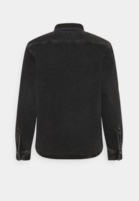 Camisa de mezclilla negra con mangas largas, cuello abotonado y dobladillo curvado. Tejido texturizado con costuras visibles y detalles de botones.