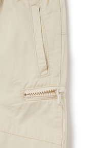 Pantalones beige con un bolsillo con cremallera y un tirador texturizado, y un bolsillo en la costura lateral con un acabado y costuras limpias.