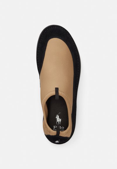 Καφέ παπούτσι χωρίς κορδόνια με λείο επάνω μέρος και μαύρη σουέτ επένδυση. Διαθέτει λογότυπο στην εσωτερική σόλα και υφή κατά μήκος της άκρης της σόλας.