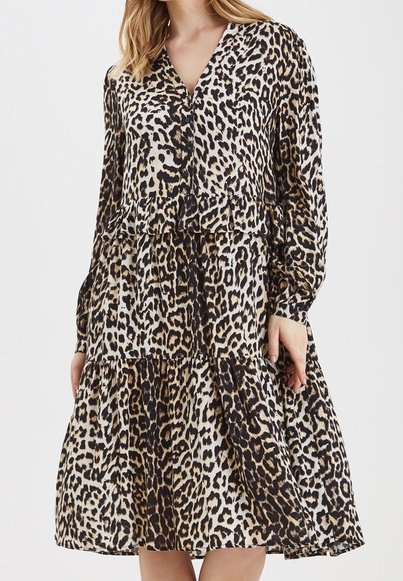 Klänning i leopardtryck i lätt material, med lagerdesign, långa ärmar och v-ringning. Färgerna inkluderar beige, svart och brunt.