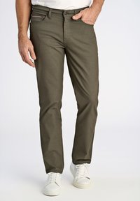 Pantalons vert olive texturés, ajustés et à cinq poches, associés à des baskets blanches. Présente des coutures discrètes et des garnitures en métal.
