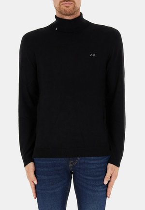 Maglione a collo alto nero realizzato in un tessuto a maglia liscia, con un design aderente e un logo discreto sul petto. Maniche lunghe, orlo a costine.