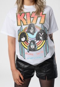 White cotton t-shirt featuring a colorful graphic of four band members, with bold black lettering for "KISS" and retro circular design elements.