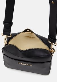 Czarna skórzana torba na ramię z złotym suwakiem i elementami ozdobnymi. Charakteryzuje się gładką fakturą, górnym zamknięciem na zamek oraz markowym wnętrzem podszytym materiałem.