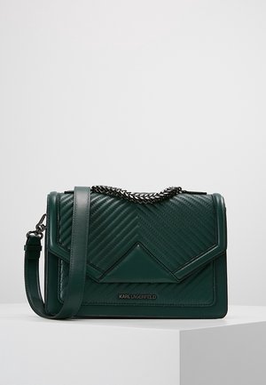 Sac à main en cuir matelassé vert foncé avec fermeture à rabat, poignée chaîne argentée, bandoulière amovible et logo Karl Lagerfeld sur le devant.