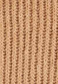 Beige stickad tyg med vertikal ribbning, med en mjuk textur och lätt fluffig yta som framhäver dess värme och komfort.