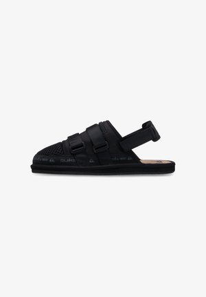 Black slip-on sandals with adjustable straps, rubber sole, mesh panels, and cork footbed for comfort and ventilation.