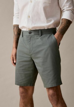 Olive green shorts made from lightweight fabric; features a button closure, side pockets, and a straight cut design.