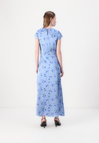 Light blue floral maxi dress with short sleeves, featuring green and purple patterns, a keyhole back detail, and a flowy silhouette.