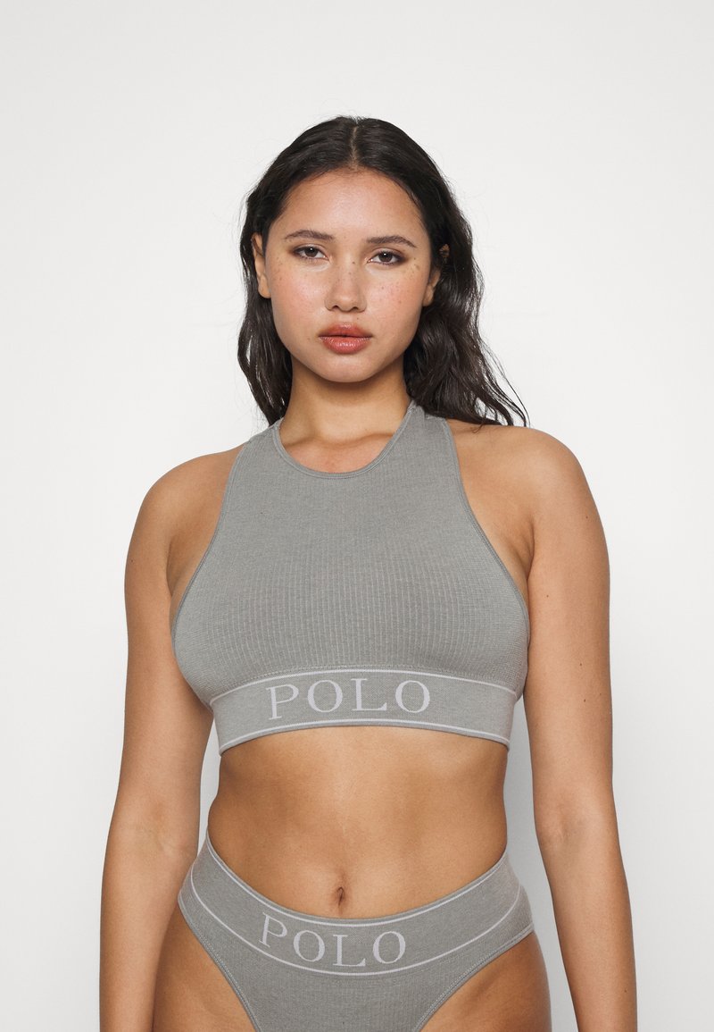 Pelēks ribots crop top ar apaļu kakla izgriezumu un elastīgu jostu, uz kuras ir uzraksts "POLO" gaismā pelēkā krāsā. Atbilstošas augstās jostas bikses.