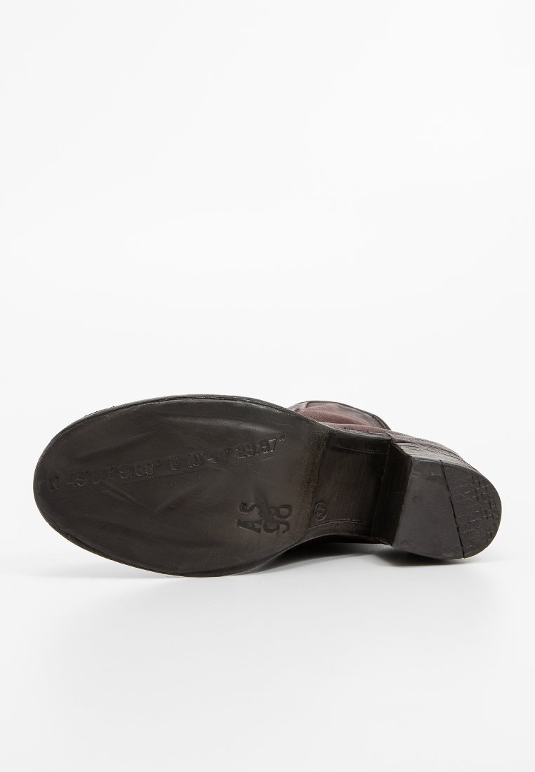 Smeđa kožna potplat cipele, pomalo istrošen sa teksturiranim crnim gumiranim donji i otisnutim oznakama. Dizajn s okruglim prstom, čvrsti potplat.