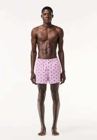 Pantaloni da bagno rosa con motivi a foglia verde, vita elastica e cordoncino, realizzati in tessuto leggero, adatti per il mare.