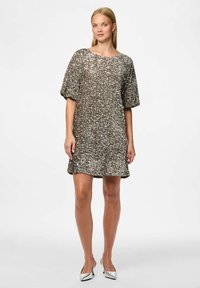 Třpytivé stříbrné šaty poseté flitry s volným střihem, lodičkovým výstřihem a krátkými rukávy. Materiál má texturovaný, reflexní povrch a zakončení ve tvaru vlnky.