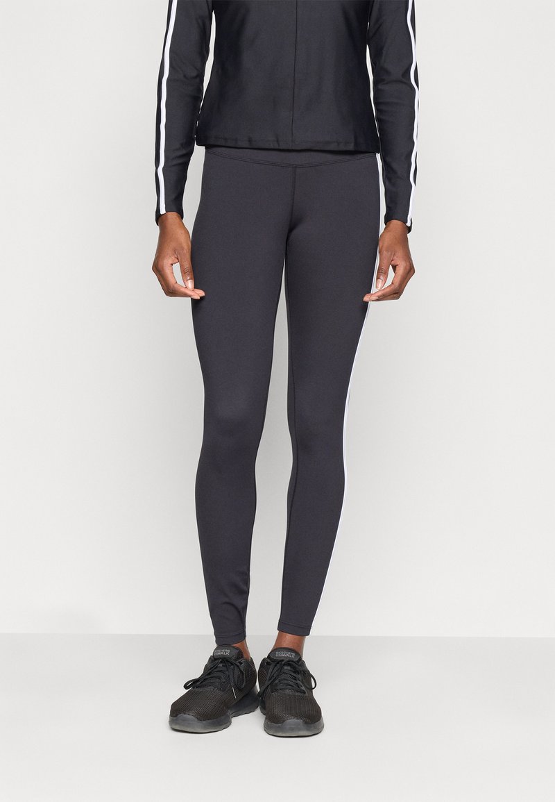 Leggings neri in un design aderente con una texture liscia e strisce laterali bianche. Abbinati a una giacca nera e scarpe da ginnastica nere.
