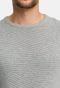 Jasnoszary sweter z dzianiny z prążkowaną strukturą, okrągłym dekoltem i diagonalnymi wzorami z przodu.