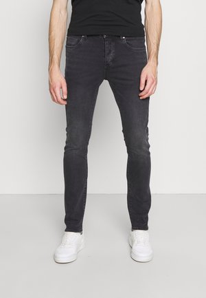 Svarta denimjeans med en smal passform, med fem fickor, subtil blekning och kontrasterande sömmar, tillsammans med vita sneakers.