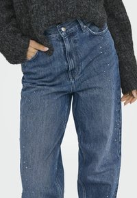 Buzunarile de denim cu talie inalta, de culoare bleu deschis, cu paiete dispersate pe partea din fata, avand un stil clasic cu cinci buzunare si inchidere cu nasture.