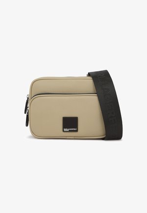 Sac bandoulière beige en matériau texturé, doté d'une fermeture éclair, d'une plaque logo noire et d'une large sangle avec marquage embossé.