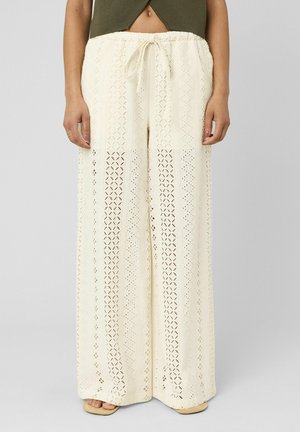 Pantalon à jambes larges en crochet crème taille haute avec taille à cordon, porté avec des sandales marron clair et un top court vert olive.