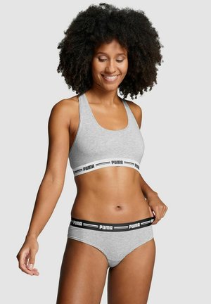 Grauer Sport-Bralette mit einem weißen Bündchen, auf dem der schwarze "PUMA"-Schriftzug zu sehen ist, kombiniert mit passendem grauen Unterhosen, beide aus einem weichen, dehnbaren Stoff gefertigt.