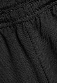Pantaloni sportivi neri con vita elastica dal texture arricciata e tessuto leggero e liscio. Nessun dettaglio aggiuntivo visibile.