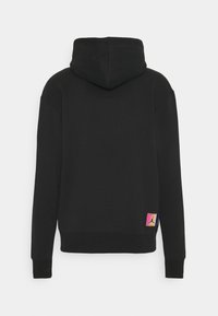 Sudadera negra con un bolsillo canguro, puños acanalados y un parche con logo en multicolor en la parte inferior izquierda. Fabricada con tejido suave y duradero.