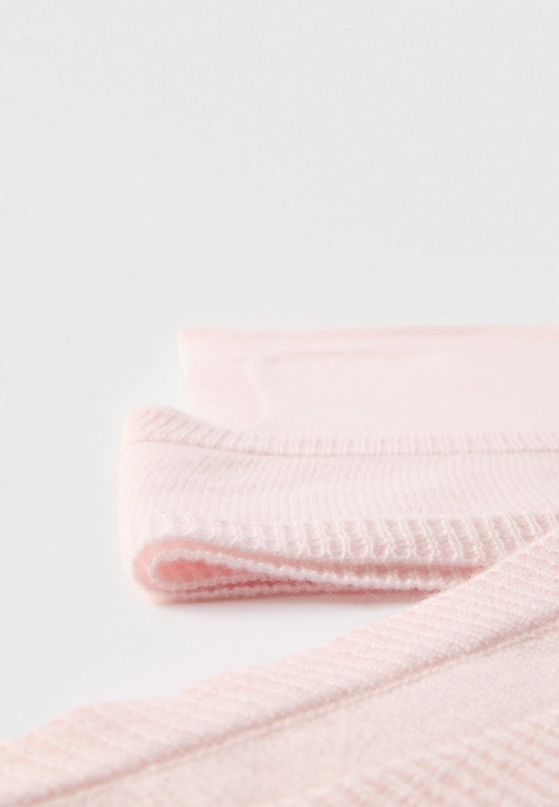 Light pink fabric with a soft texture; folded edges exhibit ribbed detailing and smooth finish; suitable for a variety of clothing items.