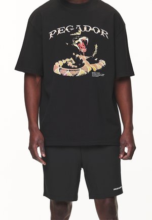 Czarny bawełniany t-shirt z wielokolorowym wzorem węża i wyraźnym napisem "PEGADOR". W komplecie czarne szorty z logo "PEGADOR".