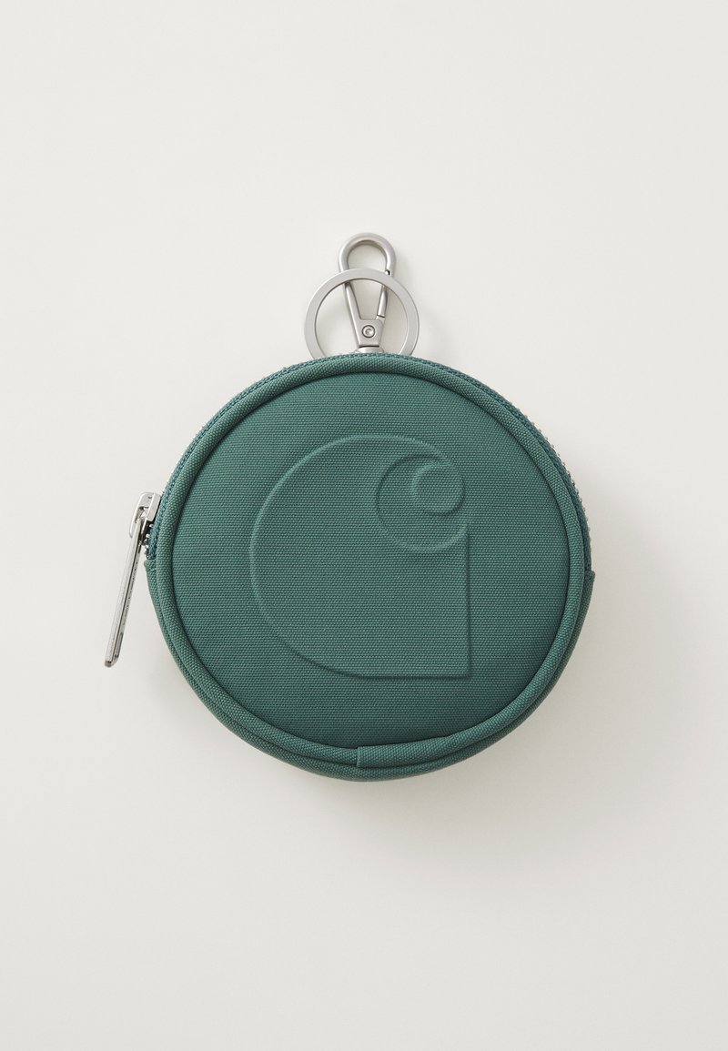 Saco redondo de tecido teal com um logótipo texturizado, fecho com zíper e um gancho prateado. Superfície lisa, design compacto, prático para armazenamento.