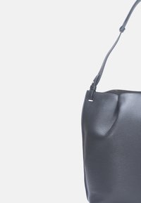 Sac seau en cuir noir avec une finition texturée et un sommet incurvé. Dispose d'une bandoulière unique et d'un discret accent métallique.