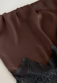 Tissu en satin brun avec texture pliée et bordure en dentelle florale noire à bords festonnés sur un fond clair.