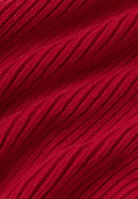 Primo piano di un tessuto lavorato a maglia rosso con texture a coste diagonali e un aspetto morbido e accogliente.