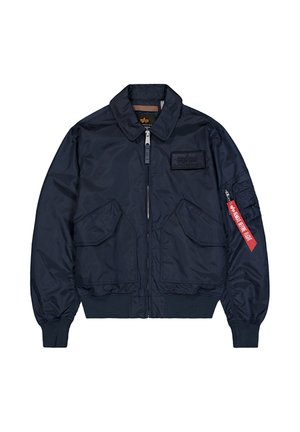 Marineblaue Bomberjacke mit vorderen Klappentaschen, gerippten Bündchen und Saum, Reißverschluss und einem roten "Remove Before Flight"-Anhänger an der linken Ärmeltasche.