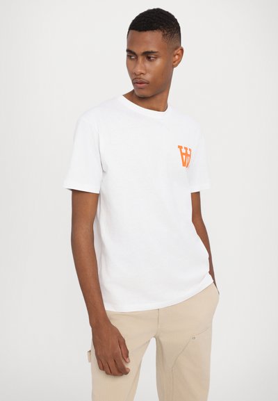 Hvid bomulds T-shirt med rund halsudskæring og korte ærmer. Har et lille orange grafisk logo på venstre bryst.