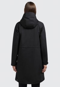 Musta vedenpitävä parka, jossa on huppu, pitkät hihat ja suora leikkaus. Ominaisuuksiin kuuluu sileä pinta ja takana kiristettävä vyötärö.
