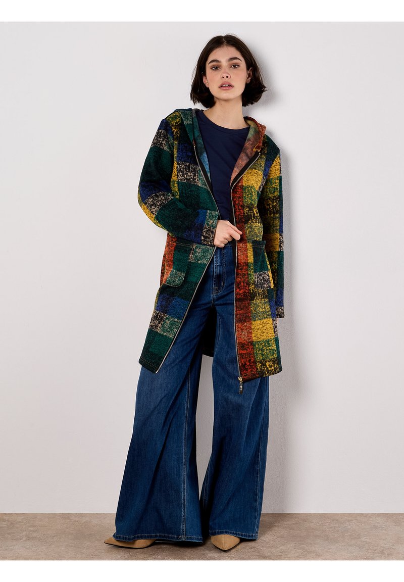 Mehrfarbiger karierter Mantel mit Kapuze, der grüne, gelbe, blaue und rote Quadrate zeigt. Die Materialien wirken strukturiert und der Mantel hat einen Reißverschluss und Taschen auf der Vorderseite.