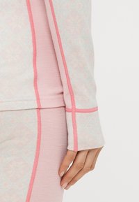 Μπλούζα με μακριά μανίκια σε απαλό ροζ χρώμα με μαλακή, διακοσμημένη επιφάνεια· διαθέτει αντίθετες ροζ ραφές και εφαρμοστή γραμμή.