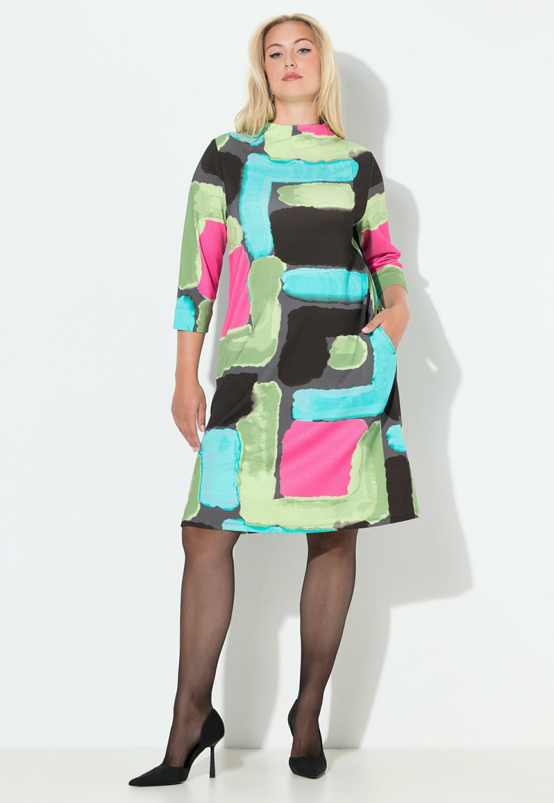Värikäs mekko, jossa on muotoja vaaleanpunaisena, vihreänä ja sinisenä tummalla pohjalla. Pitkät hihat, pyöreä pääntie ja sivutaskut.