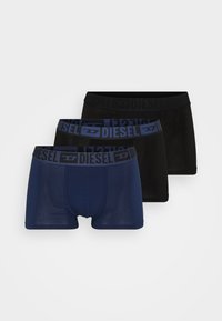 Trois paires de boxers : un bleu marine avec une ceinture bleue, un noir avec une ceinture noire, et un bleu marine foncé avec un logo bleu.